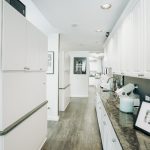 A clean, white clinical hallway with laboratory equipment and cabinetry organized for dental procedures.