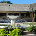 Wide shot of the dental office building featuring a manicured garden and a small decorative fountain in the foreground
