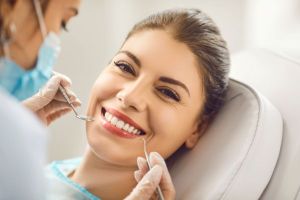 Woman smiling at dental professional while receiving a dental check-up with dental tools close to her mouth